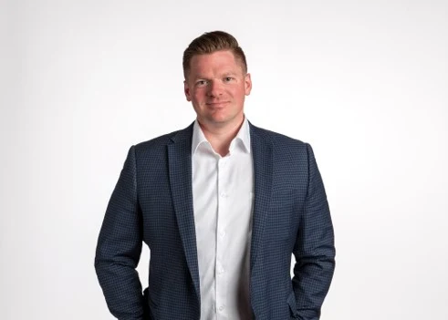 Daniel Sirski, Winnipeg Realtor with CENTURY 21 Carrie Realty, in a navy patterned blazer and open-collar white shirt against a light studio background
